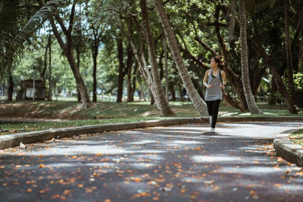 Babaeng Asyano na nagjo-jogging sa luntiang parke
